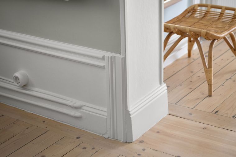 Plinthe blanche moulurée le long d'un parquet