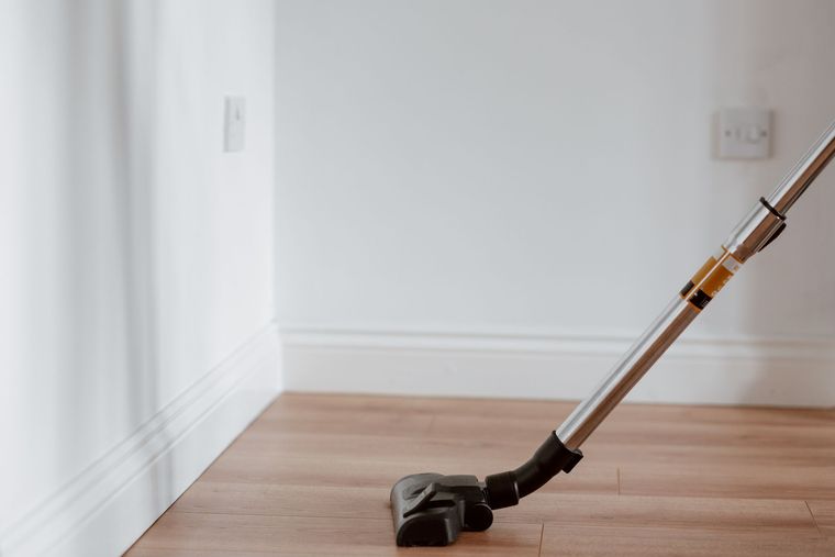 Aspirateur passé le long d'une plinthe, sur un parquet