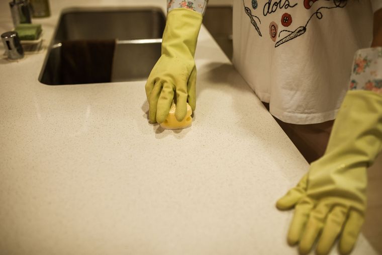 Mains en gants de ménage jaunes nettoyant un plan de travail de cuisine