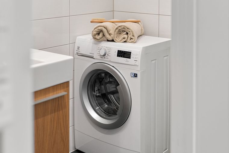 Lave-linge dans une salle de bain, serviettes posées dessus