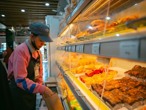 Employée de boulangerie rangeant des viennoiseries en vitrine