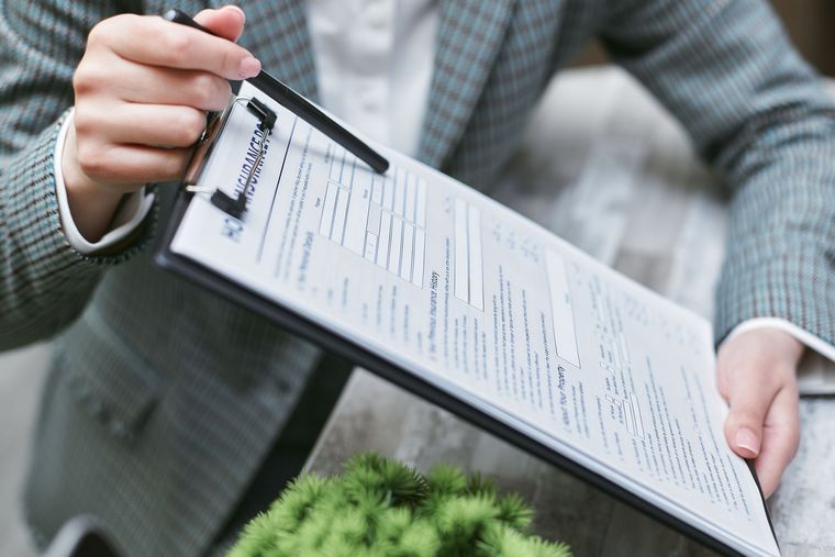 Main tenant un porte-documents avec un formulaire à remplir