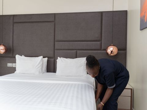 Employé d'hôtel préparant un lit dans une chambre