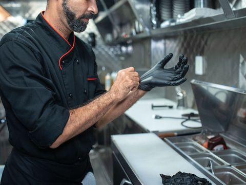 Cuisinier enfilant des gants dans une cuisine professionnelle