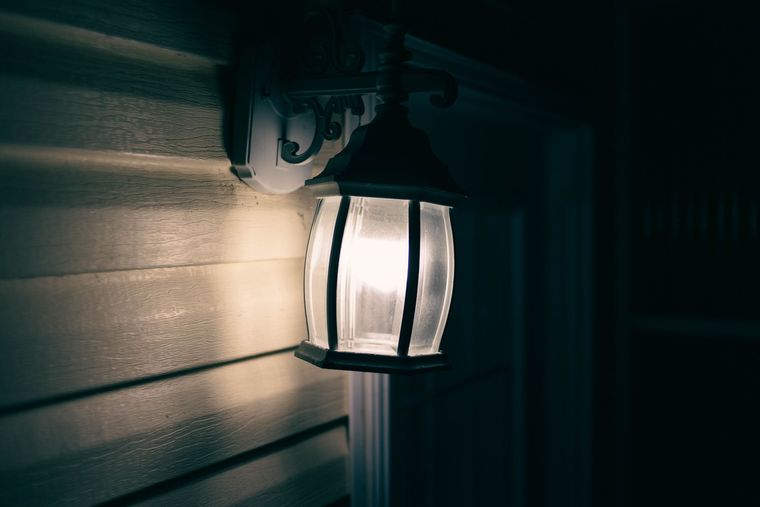 Applique extérieure allumée sur un bardage en bois, la nuit